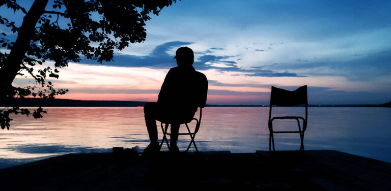 Building an Evening Routine for Peak Performance Preservation - silhouette of man sitting by a lake